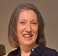 Jo Williams, a white woman with shoulder-length brown hair, wearing a black shirt, looking at the camera and smiling