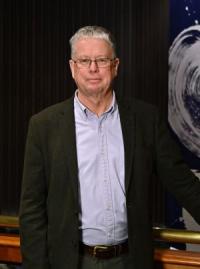 David Dale, a white man in his late fifties, with short grey hair and glasses, wearing a dark grey jacket and pale shirt, looking at the camera.