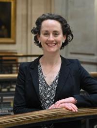 Sophie Broadfield, a white woman in her late thirties/early forties, with short dark hair, wearing a dark jacket and patterned blouse, looking at the camera and smiling.