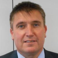 Mark Jackson, a white man in his forties with very short dark hair and blue eyes, looking at the camera